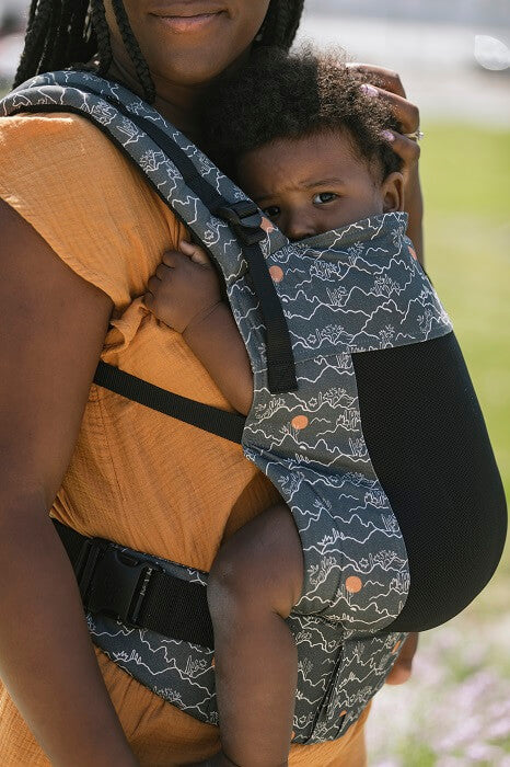 Closeup photo of a baby seated belly-to-belly in an ergonomic baby carrier from birth