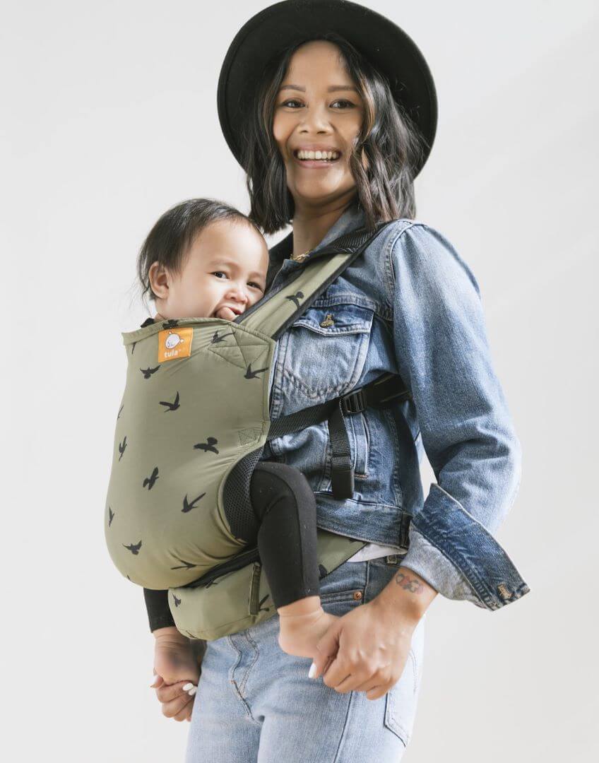 Baby in a ergonomic lightweight baby carrier with swallows in olive green.