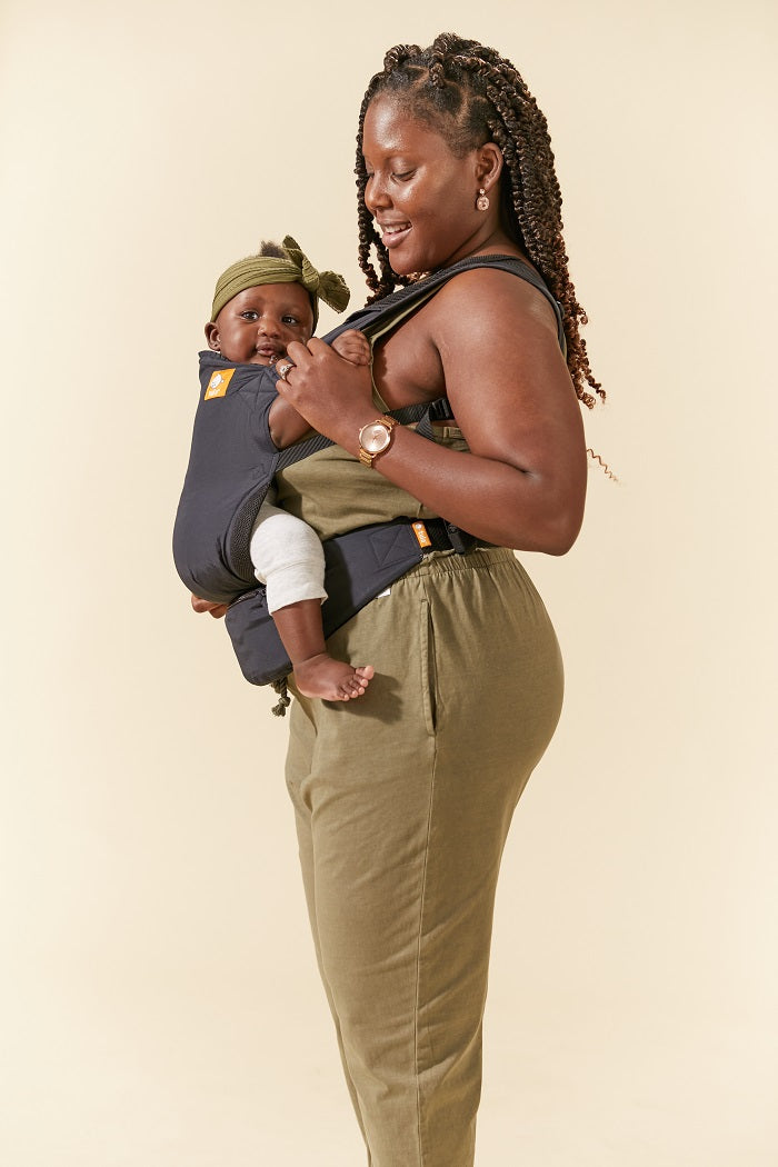 Mom carrying her child in Tula Lite compact carrier Black.
