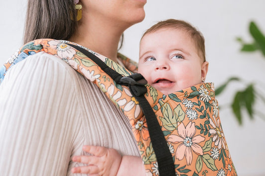 A closeup of a smiling baby in a Tula Carrier.