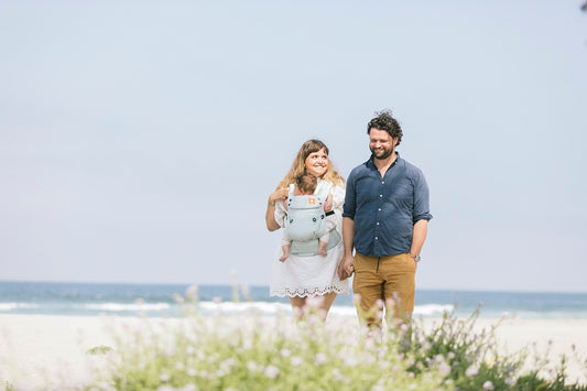 A babywearing couple on a walk at the beach.