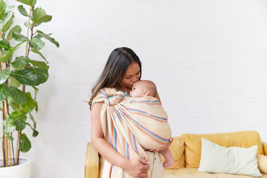 A mother kissing her child on the forehead while using a Tula Ring Sling.