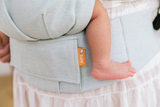 Closeup of a baby sitting in a Linen carrier.