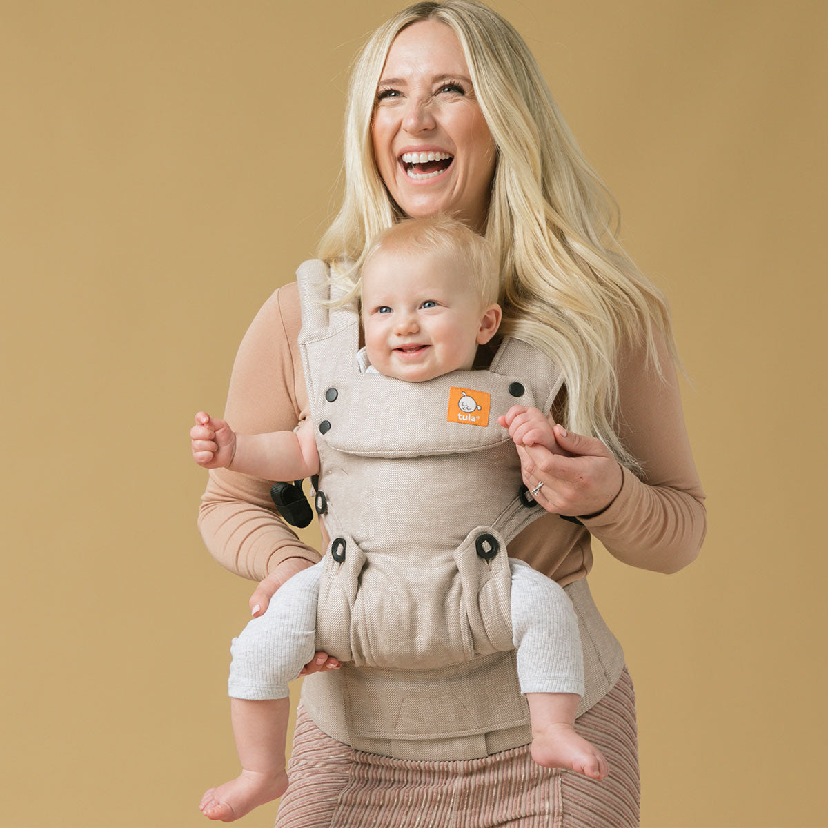 Happy mum babywearing her child in Tula Explore carrier in forward facing position