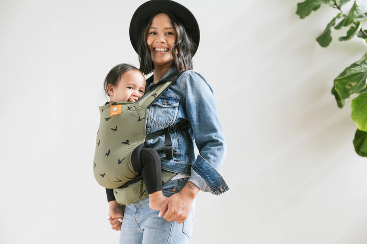 A happy mother and her child using a Tula Lite Travel Carrier.