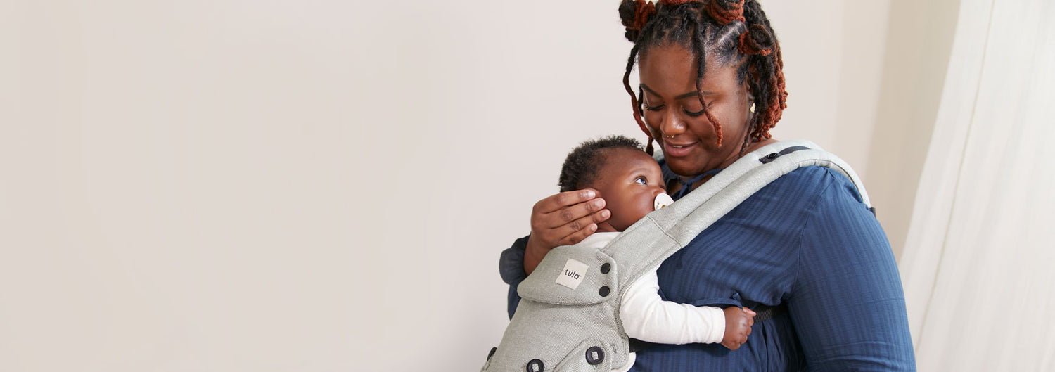 Mum smiles at her baby in Tula Explore Spruce baby carrier