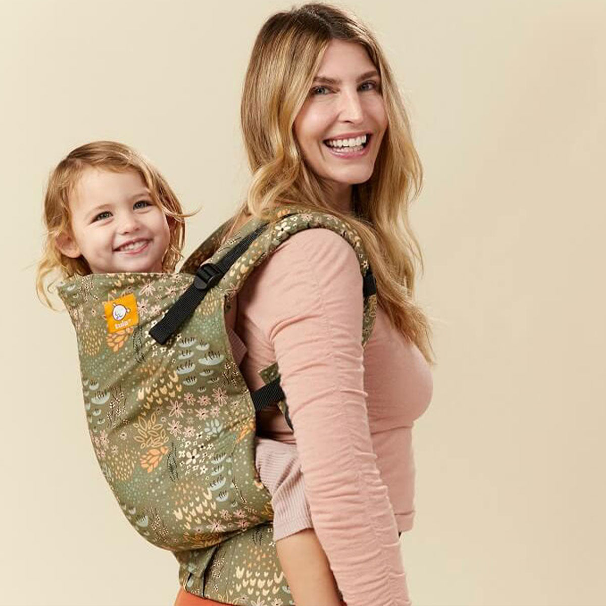 Smiling mum with her daughter sitting in a Toddler carrier on her back