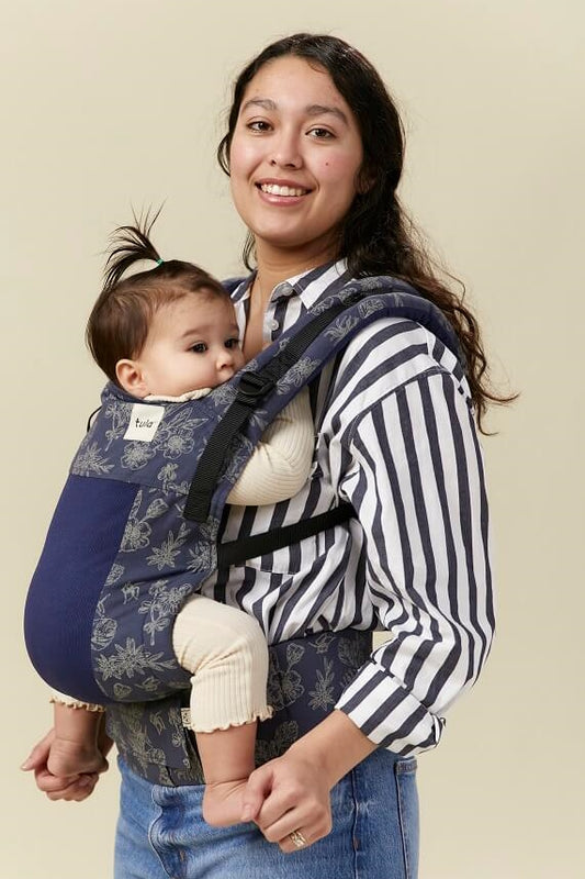 Tula Baby Carrier Coast Edelweiss with beige stenciled flowers on a navy blue background.
