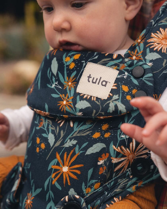 A close up photo of an infant in forward facing position Tula Explore baby carrier i