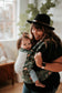 Caregiver and infant joking around in a baby carrier usable from newborn