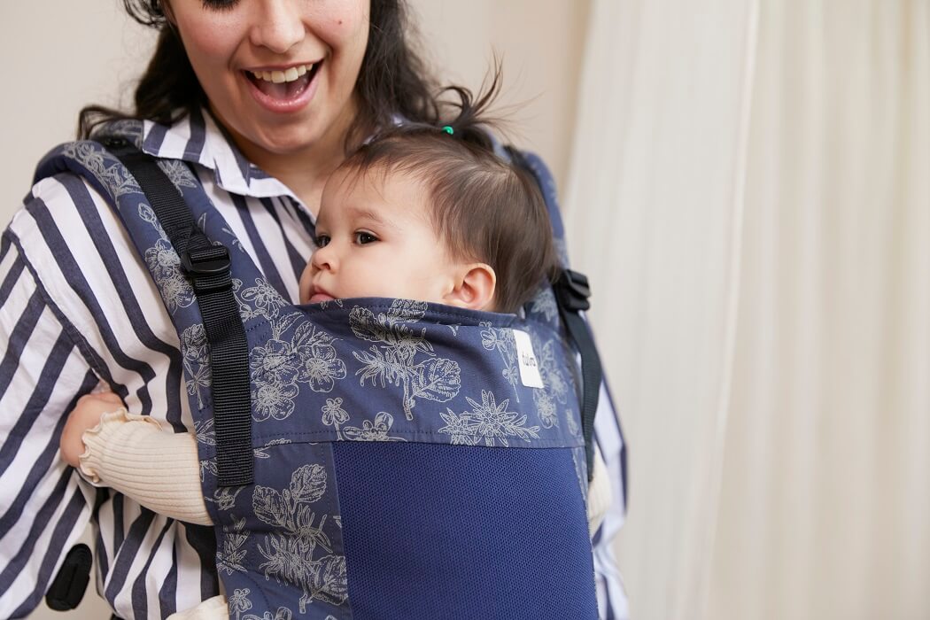A close-up photo of a mother and her child in Tula Free-to-Grow Coast Explore Baby Carrier Edelweiss