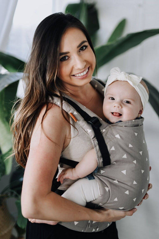 A mother and her daughter smiling into the camera while using the ergonomic Free-to-Grow Baby Carrier Sleepy Dust from Tula.