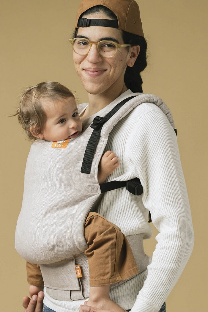 The caregiver and their baby using the ergonomic Free-to-Grow Carrier Linen Sand from Tula.