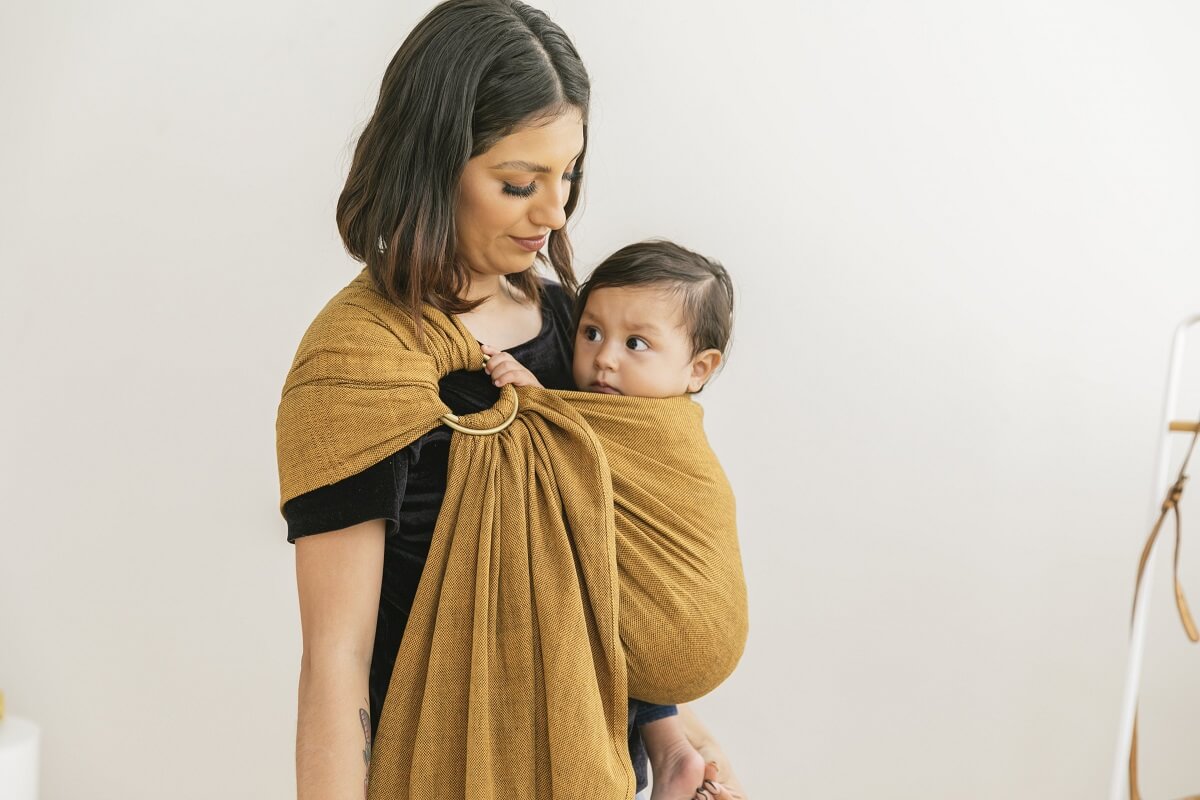 Mum wearing her infant in a Tula Ring Sling newborn carrier from Girasol Camote woven fabric.