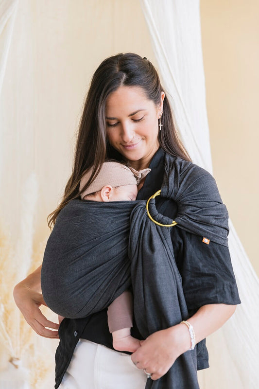 A mother carrying her baby in Tula's Ring Sling Simple Black.