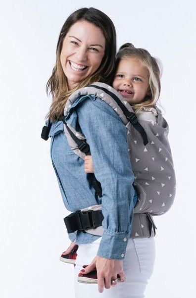 A mother carrying her daugther in the Toddler Carrier Sleepy Dust in back-carry position.