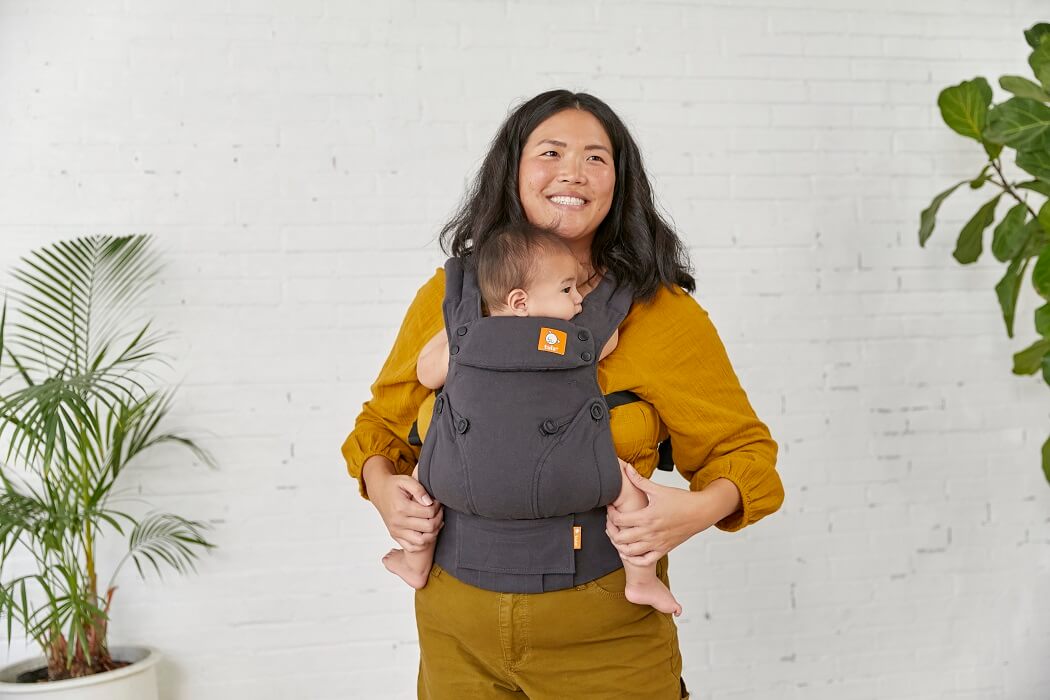 A mother carrying her child in the soft  Hemp Obsidian Explore Carrier from Tula in a front-carry position.