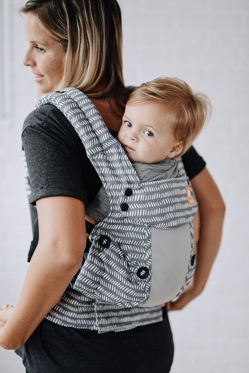 A little boy sitting in the Explore Baby Carrier Coast Beyond in back-carry position.