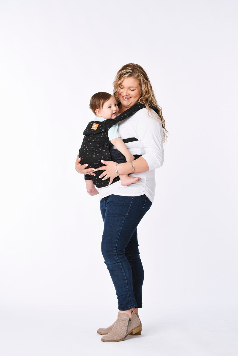 Caregiver wearing infant in an ergonomic baby carrier convenient from newborn.