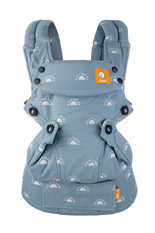 Forward-facing ergonomic Tula Explore Baby Carrier Harbor Skies, colored in light blue with a repeating sunrise illustration in a light color.