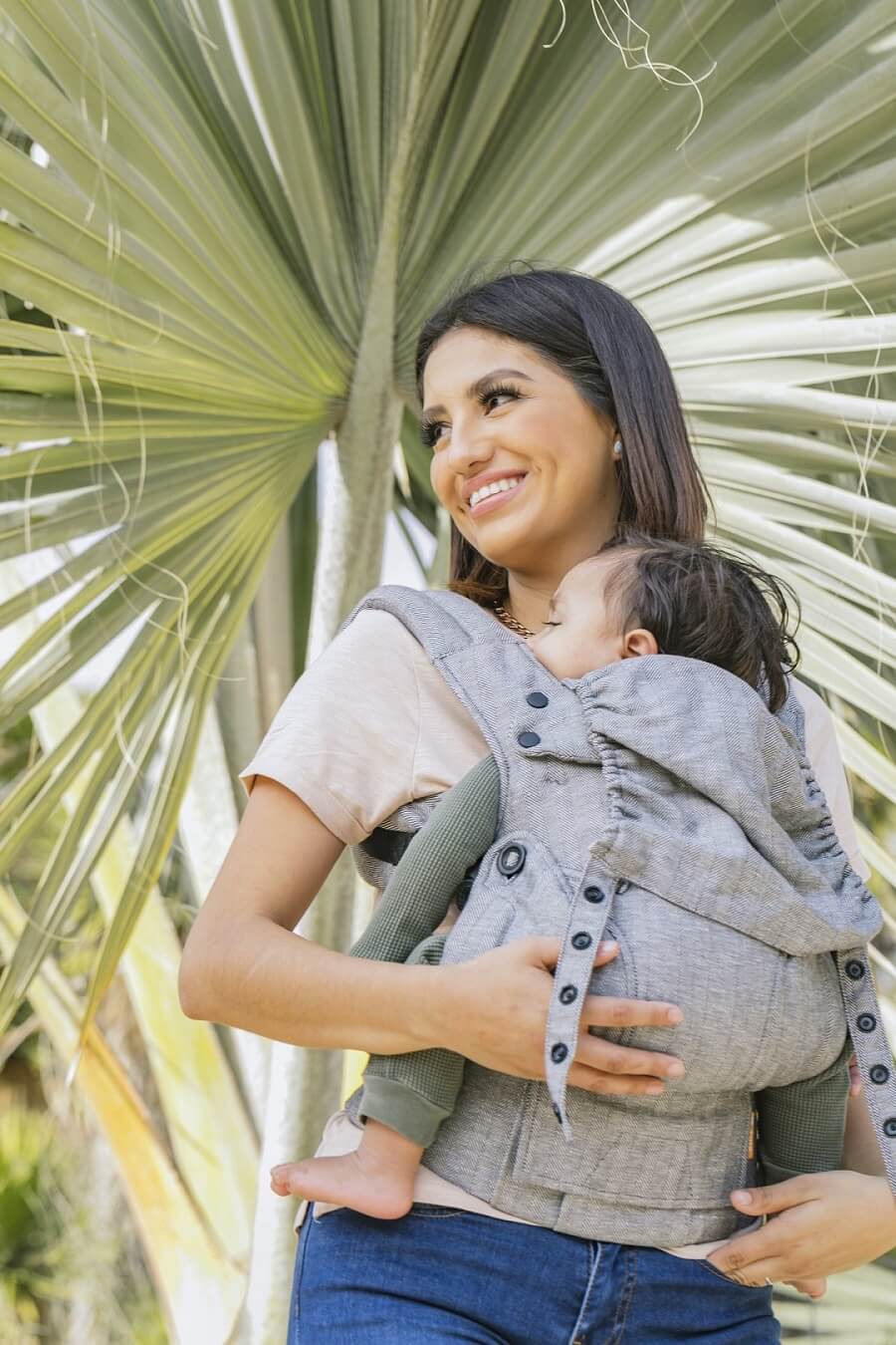 Caregiver carrying baby in Ergonomic baby carrier suitable from birth.