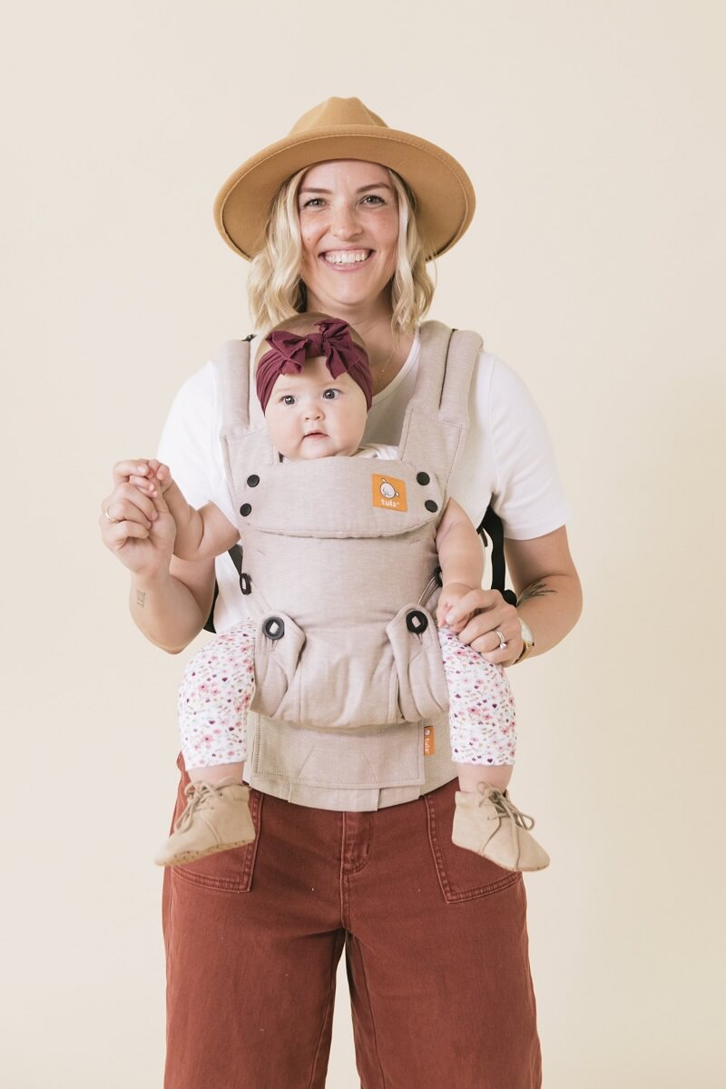Caregiver wearing baby in an ergonomic front-facing baby carrier.
