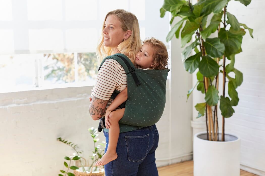 A mum carrying her child in back carry position in Baby Tula Toddler Carrier Seedling