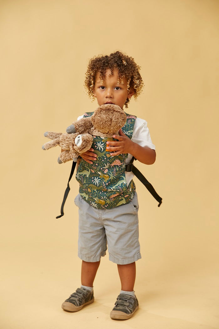 A boy carrying his toy in Tula Baby Doll Carrier in fun dinosaur print