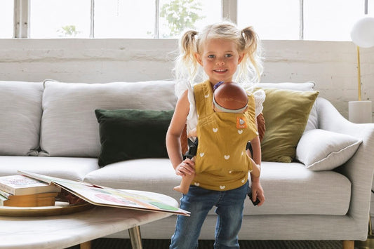 A little girl wearing the Tula Mini Doll Baby Carrier Play.
